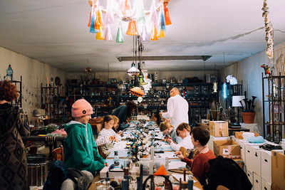 Mehrere junge Menschen sitzen an einem langen Tisch und bauen etwas.